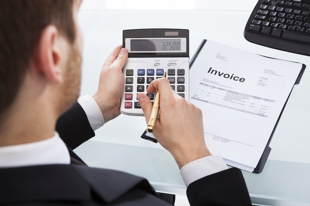 Businessman Calculating Invoice At Office Desk